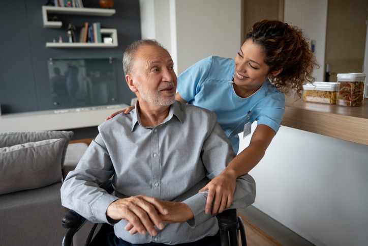 Senior man with ALS in a wheelchair talking to his home caregiver